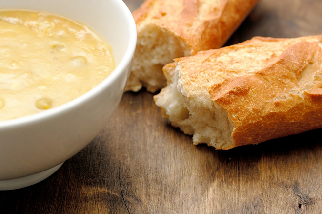 A bowl of soup and two pieces of bread.