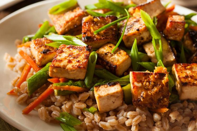 A plate with stir fried tofu and brown rice.