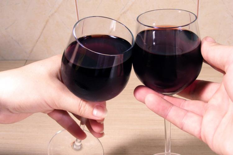 Two hands clicking glasses of red wine.