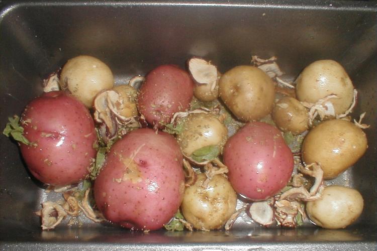 Red and white potatoes roasting in a roast pan.