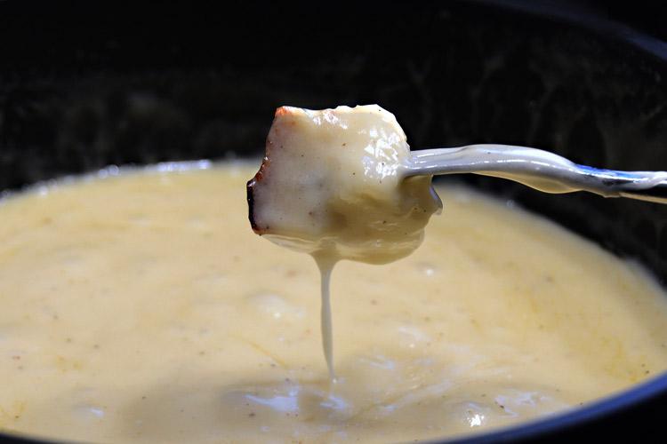 A piece of bread dipped in cheese fondue.