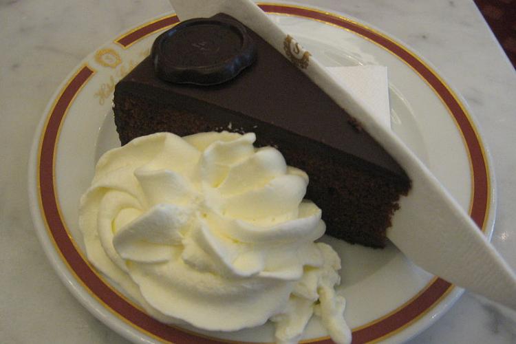 A piece of sacher torte served with whipped cream.