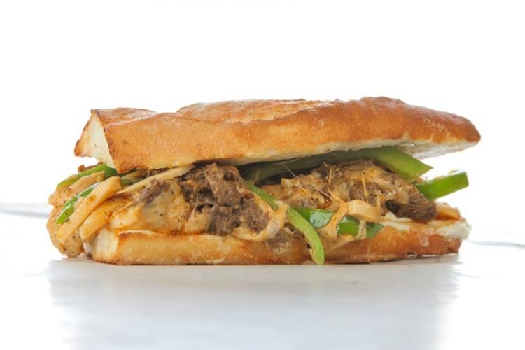 A Philly cheese steak sandwich with added green peppers.