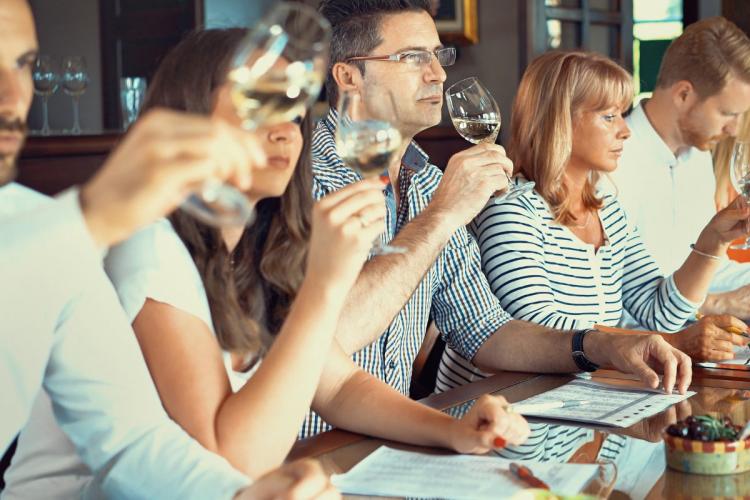 Side view of a group of adults tasting wine at a local winery. 