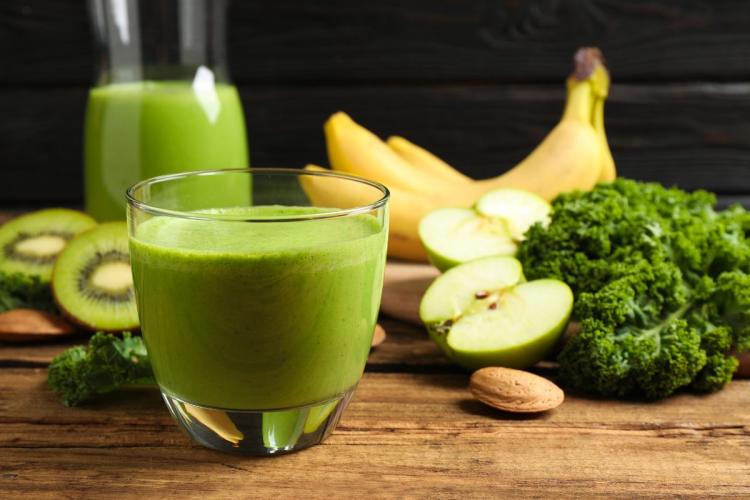 A glass of kale apple tropical smoothie with the raw ingredients around.