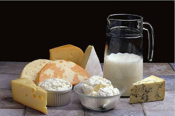 Several types of cheese and a jug with milk.