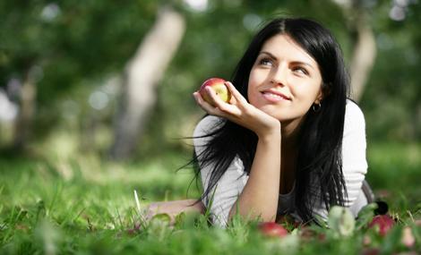 A young woman with an apple in the hand.