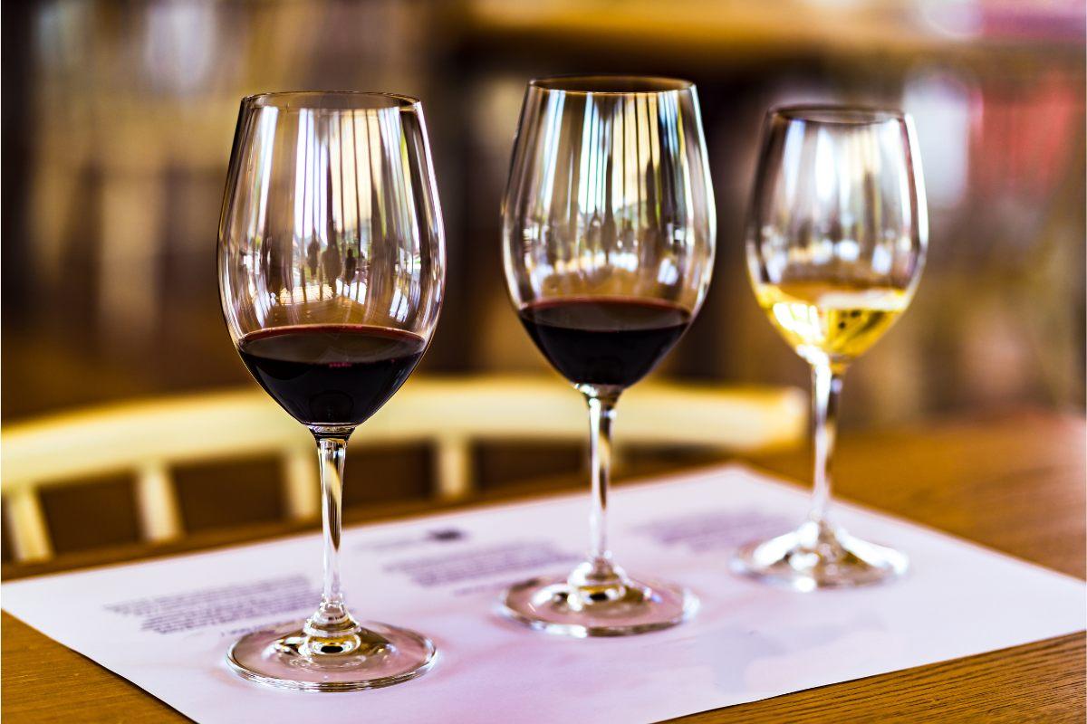 Three wine glasses ready for a wine tasting, two of the with red wine and ona with white wine.