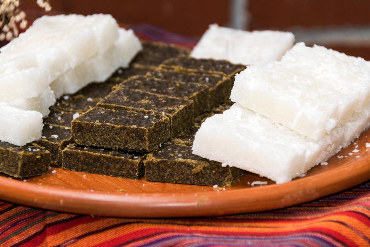 White and dark Guatemalan coconut sweets arranged on a terracotta plate.