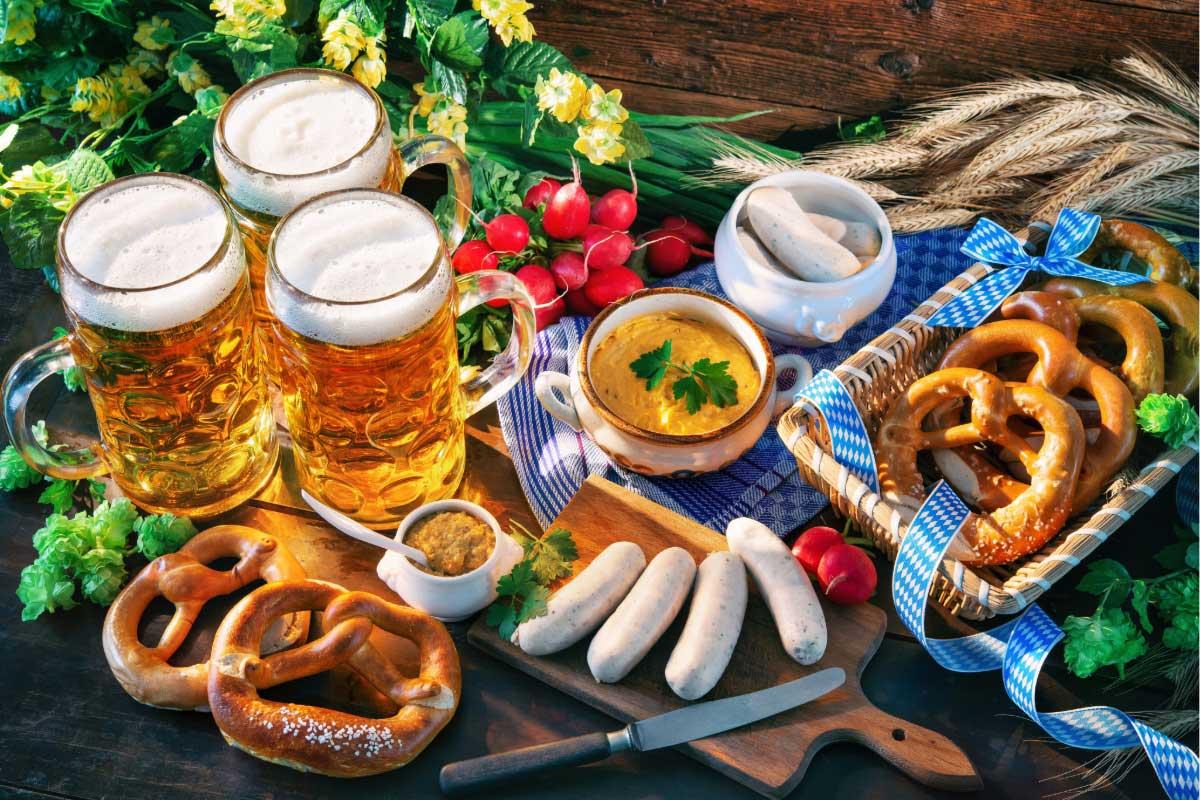 Bavarian sausages with pretzels, mustard and beer mugs on a rustic table.