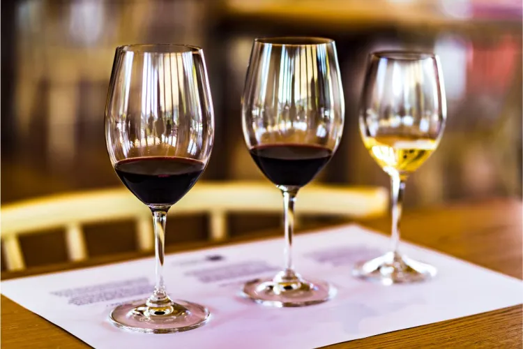 Three wine glasses ready for a wine tasting, two of the with red wine and ona with white wine.