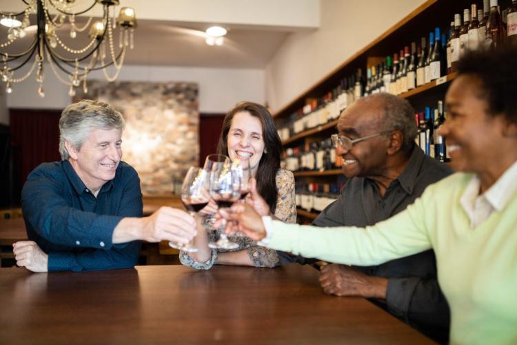A group of four friends visiting a winery and enjoying a tasting.