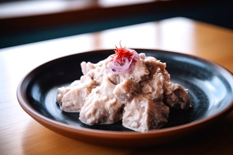 A plate of hákarl, Icelandic fermented shark, garnished with red onion slices and red shavings.