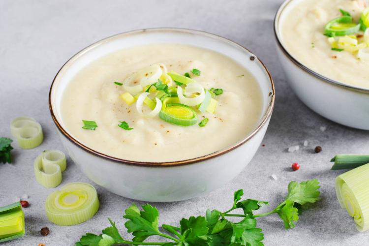 Creamy leek and potato soup garnished with fresh leeks and parsley.
