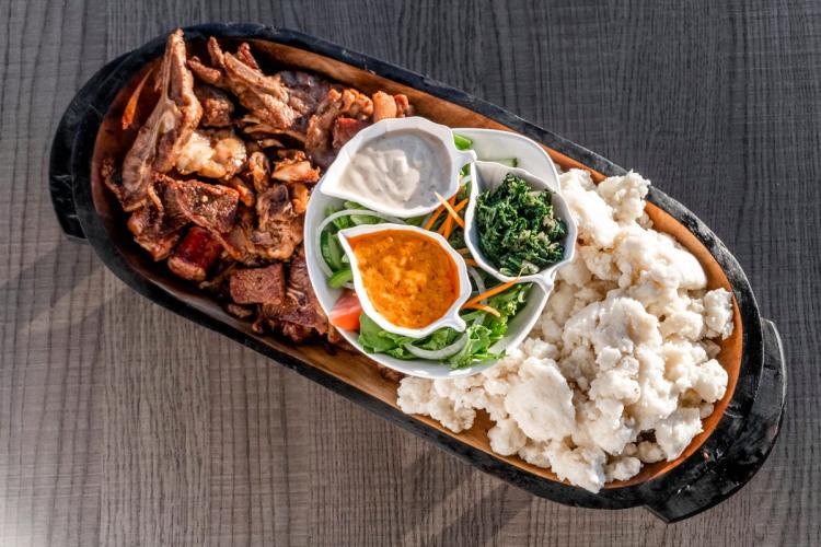 Swazi or Eswatini platter with braaied meat left, white pap right, with greens, salad, and sauces in the center.