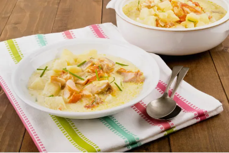 A plate of Cullen skink soup on a tea towel with a serving bowl of the same soup by the side.
