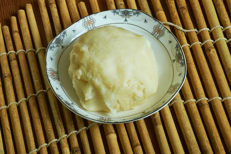 Serving of fufu on a decorative plate placed on a bamboo surface.