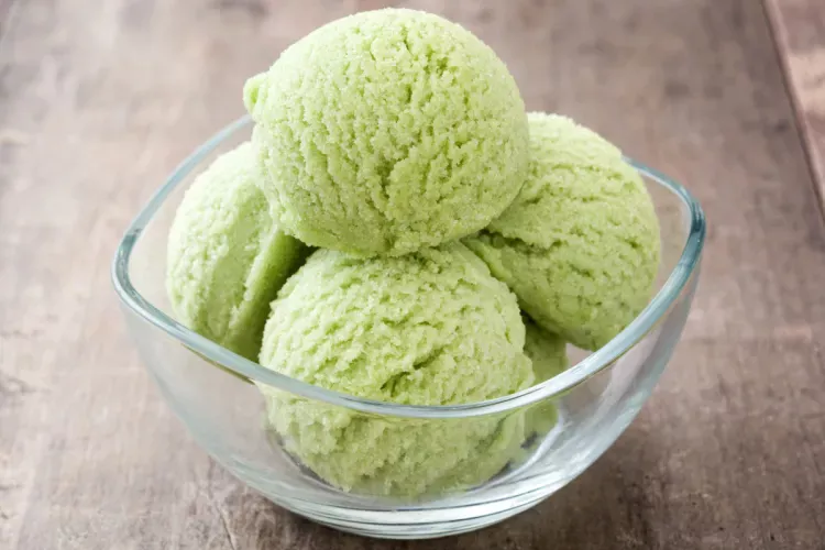 Four scoops of matcha ice cream in a glass bowl with a square rim.