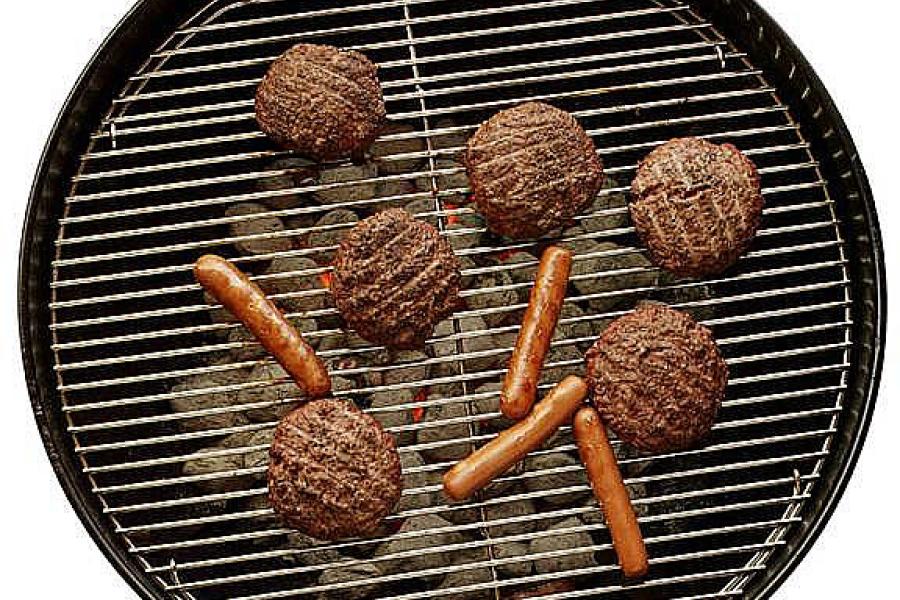Meat and sausages cooking on a charcoal barbecue.