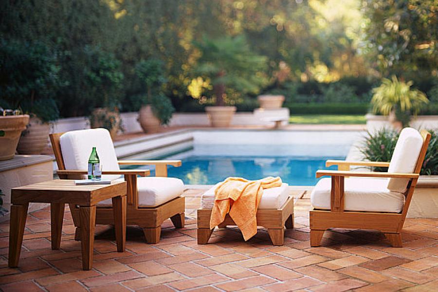 Patio furniture by the side of a swimming pool.
