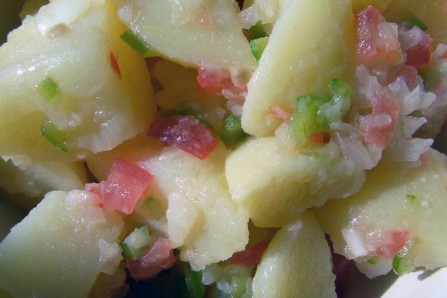 Poato salad with a dressing of vinaigrette wiht finely chopped tomato, bell pepper and onion.