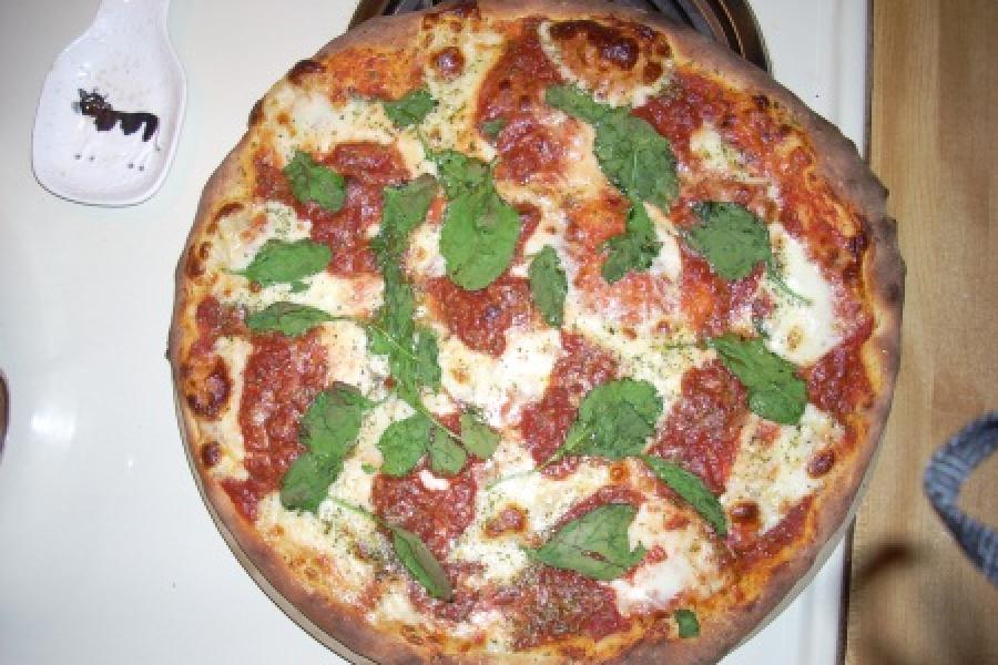 Pizza done with mozzarella and fresh basil.
