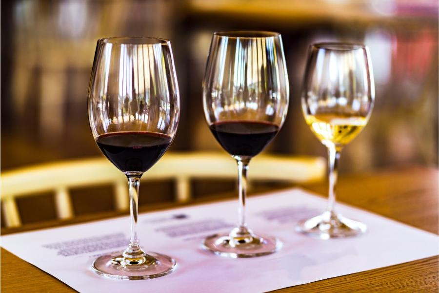 Three wine glasses ready for a wine tasting, two of the with red wine and ona with white wine.