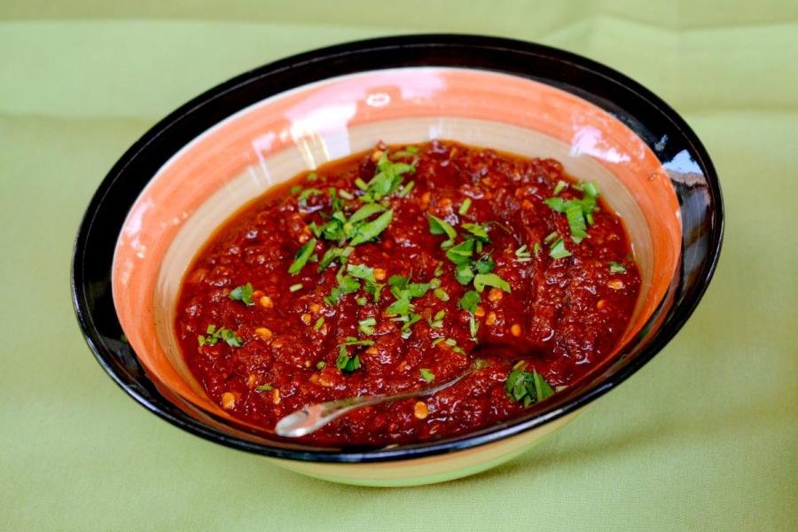 A bowl of redish pindjur dip garnished with fresh herbs.