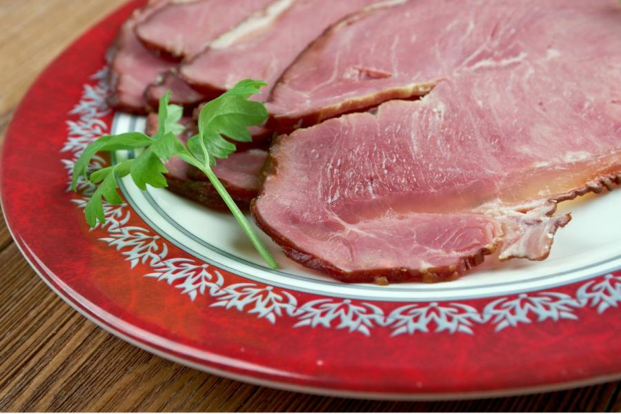 A plate of Icelandic hangikjöt, smoked lamb served with a white sauce and garnished with onions and red shavings