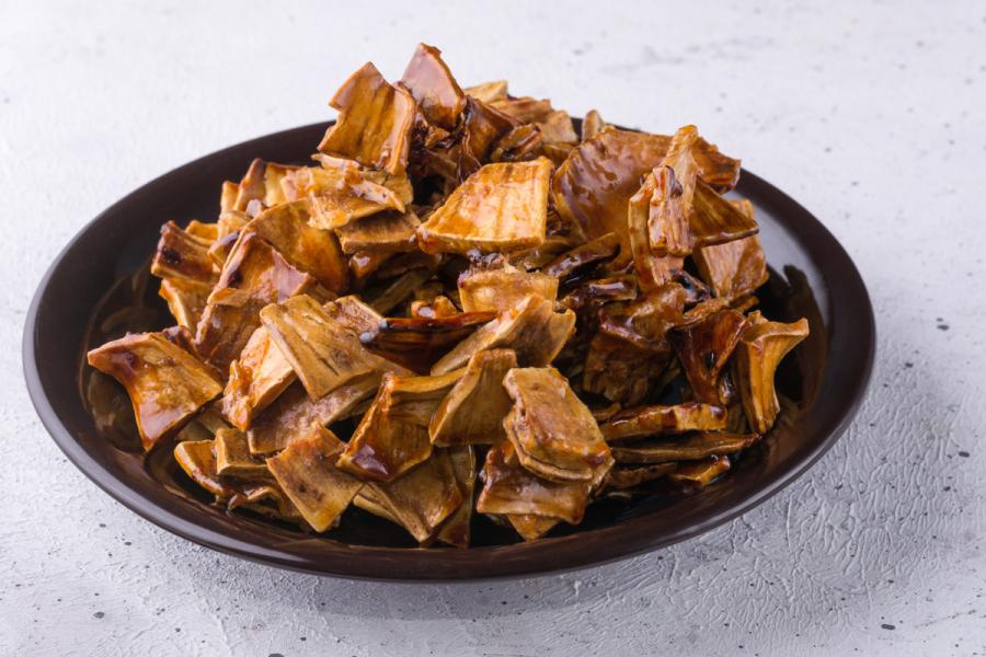 A plate with roasted breadfruit pieces mixed with sugar syrup.