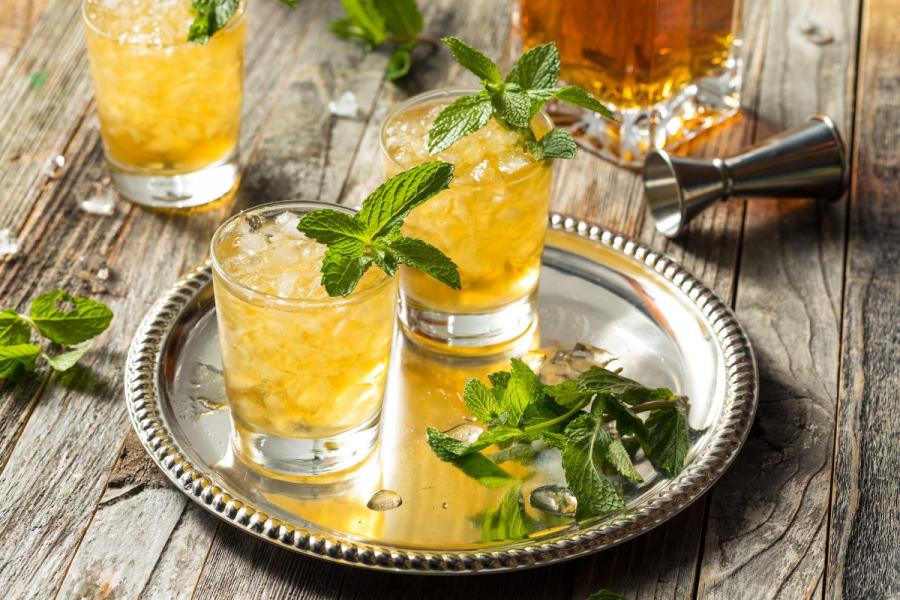 Two glasses with bourbon mint julep on a silver tray.