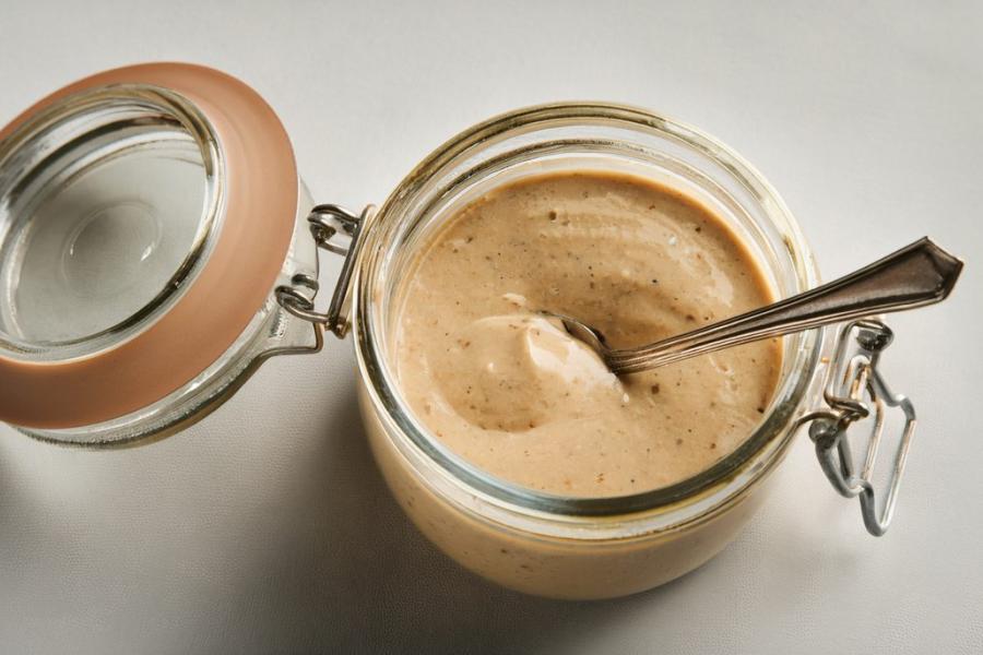 Tahini tarator sauce in a glass jar, image edited with AI.