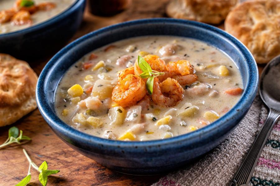Creamy shrimp and corn chowder in a blue bowl topped with seared shrimp.