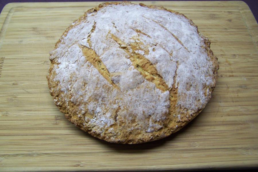 A loaf of soda bread on a wooden surface.