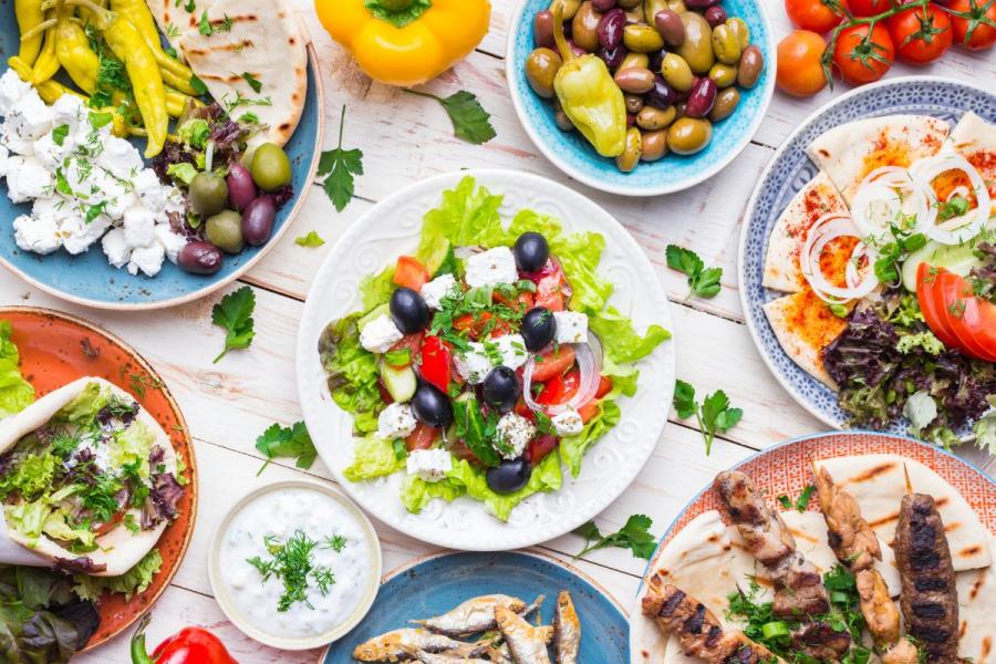 A selection of Greek food including meze, gyros, souvlaki, pita bread, Greek salad, tzatziki, feta and olives.