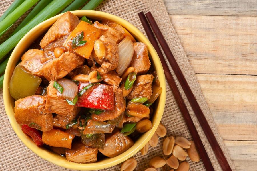 Kung pao chicken in a bowl with two chopsticks on the side.