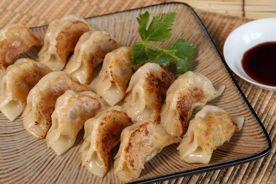 A selection of gyoza dumplings and a bowl of dipping sauce.