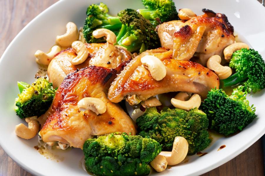 Pieces or roast lemon chicken with broccoli florets and cashew nuts.