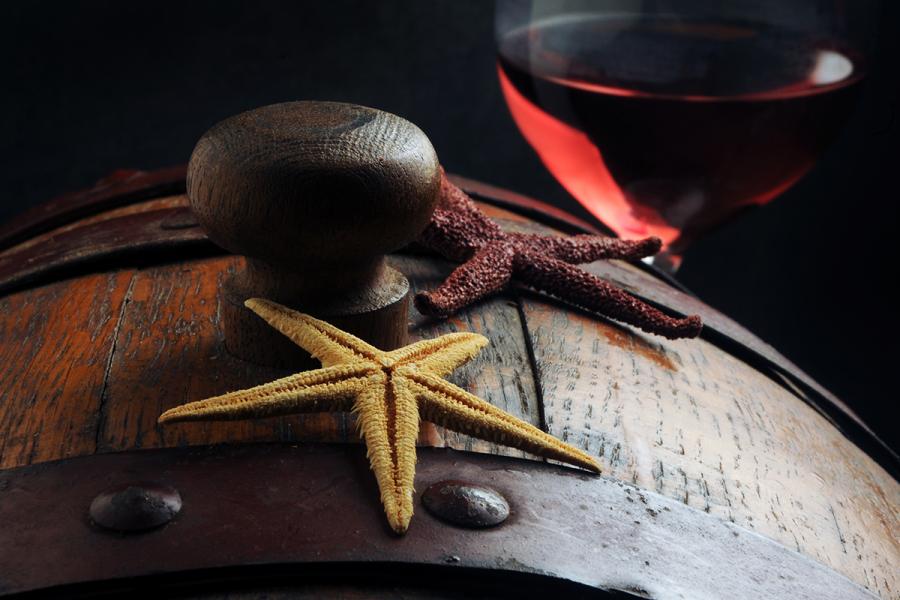 Old wine barrel with starfish on top and a glass of wine on the side.