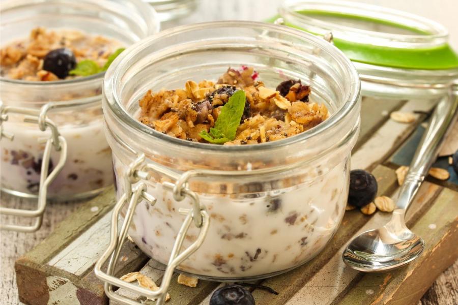 A jar of overnight oats with blueberries and nuts as toppings.